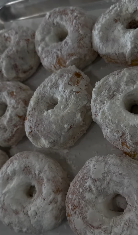 Powdered sugar donuts stacked on a tray